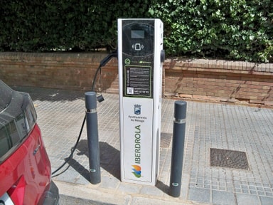 Borne de recharge Iberdrola sur un trottoir de Málaga, en Espagne, avec une voiture électrique branchée