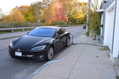 Voiture électrique en charge devant une maison grâce à une installation domestique
